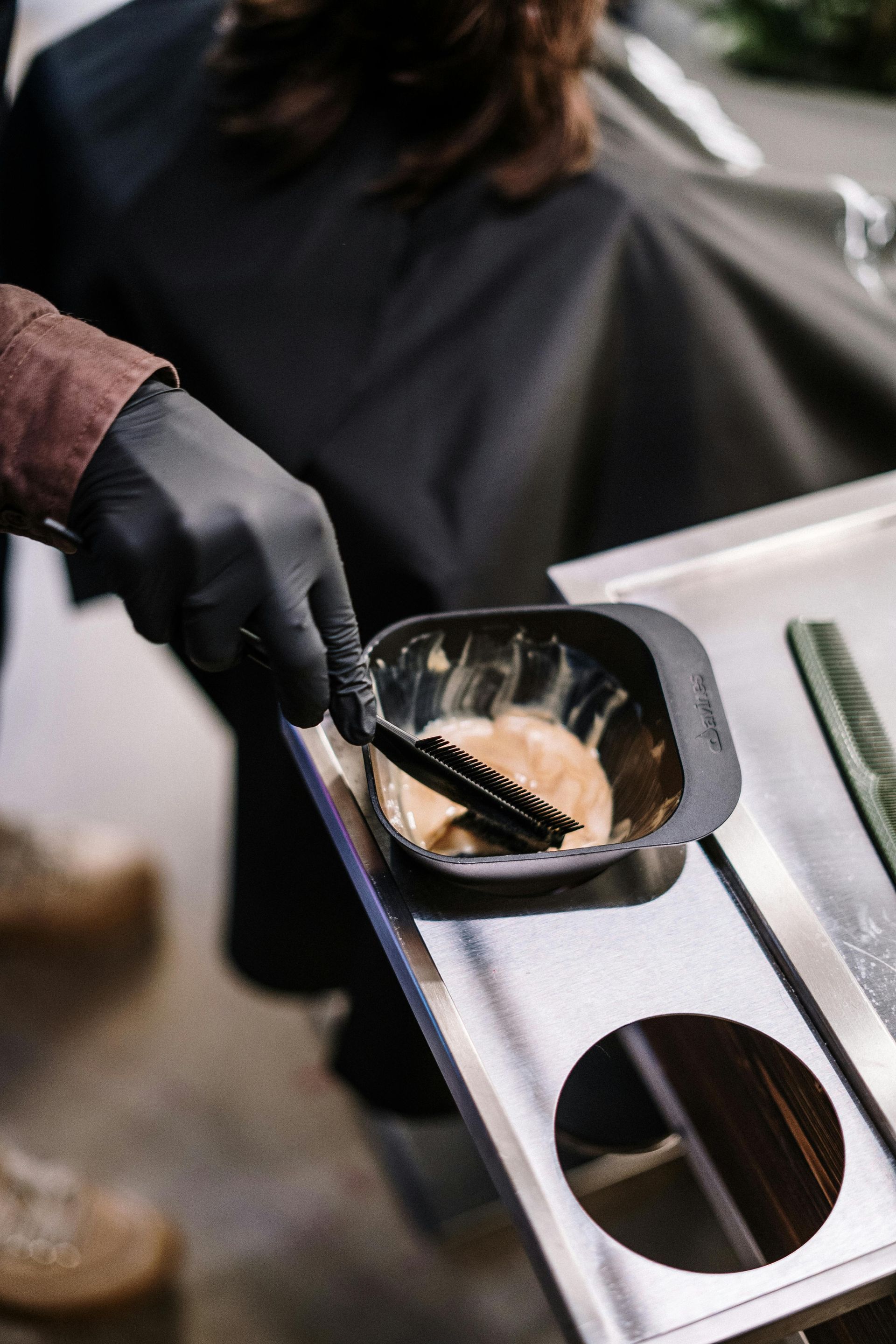 A person is holding a bowl of hair dye and a brush.