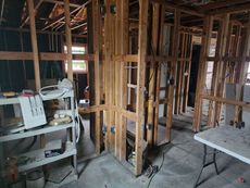 Interior room under construction with exposed wooden framing, electrical wiring, and concrete floor.