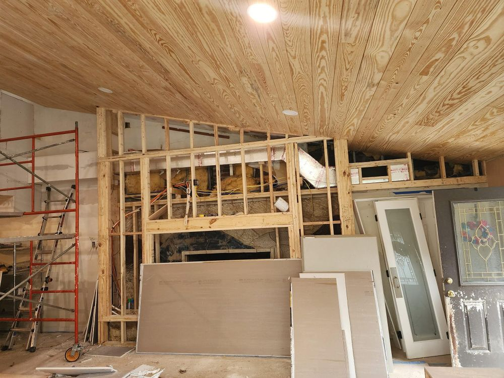 Interior construction: Framing around fireplace, wood ceiling, scaffolding, doors leaning against wall.
