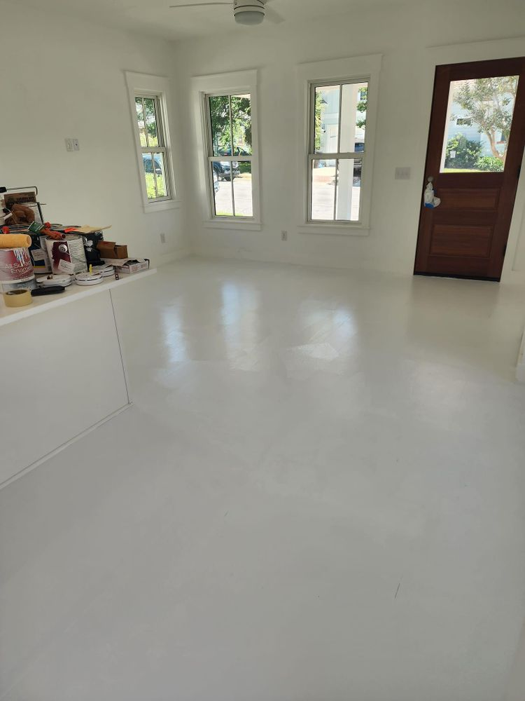 White-floored room with windows, door, and a kitchen counter with items on it.