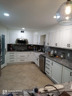 White kitchen with granite countertops and stainless steel appliances.