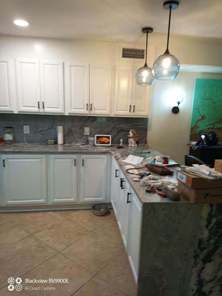 White kitchen with countertops, cabinets, and pendant lights.