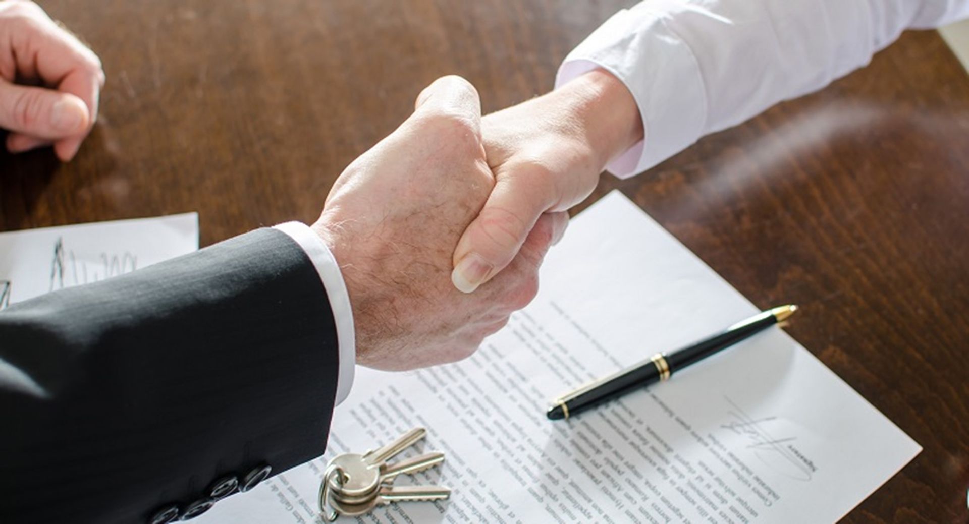 a man and a woman are shaking hands over a signed document