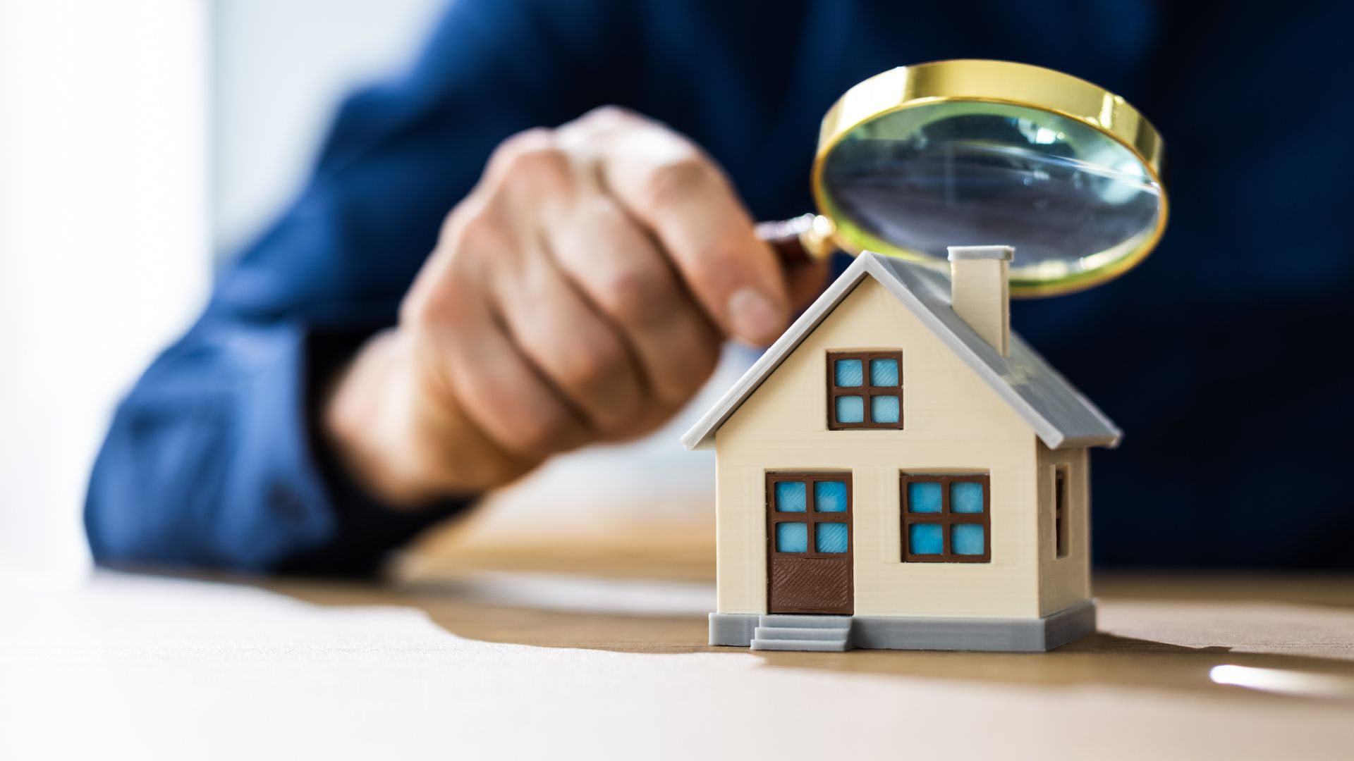 a person is looking at a model house with a magnifying glass