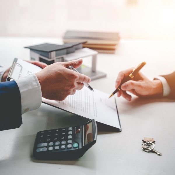 two people are sitting at a table signing a document