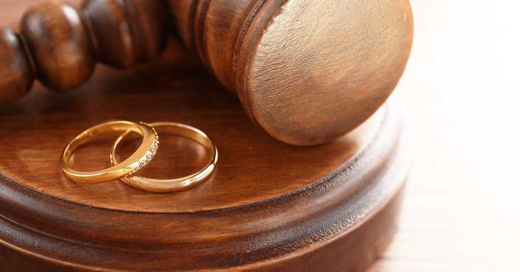 two wedding rings are sitting on top of a wooden gavel