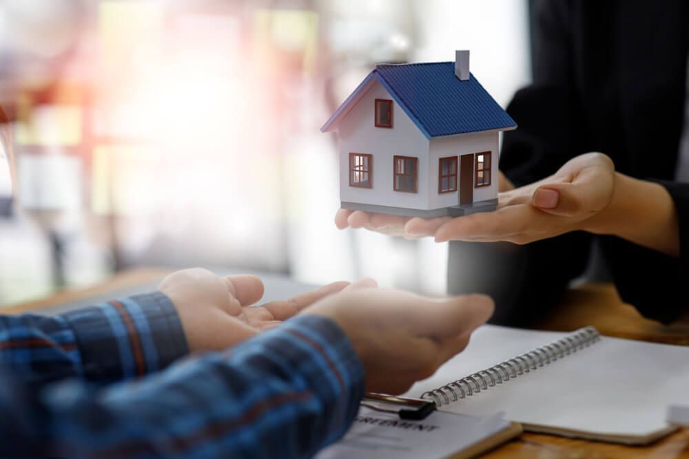 a person is holding a model house in their hands