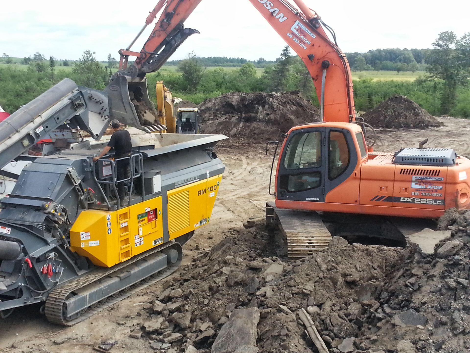 Une grande excavatrice orange creuse dans un tas de terre