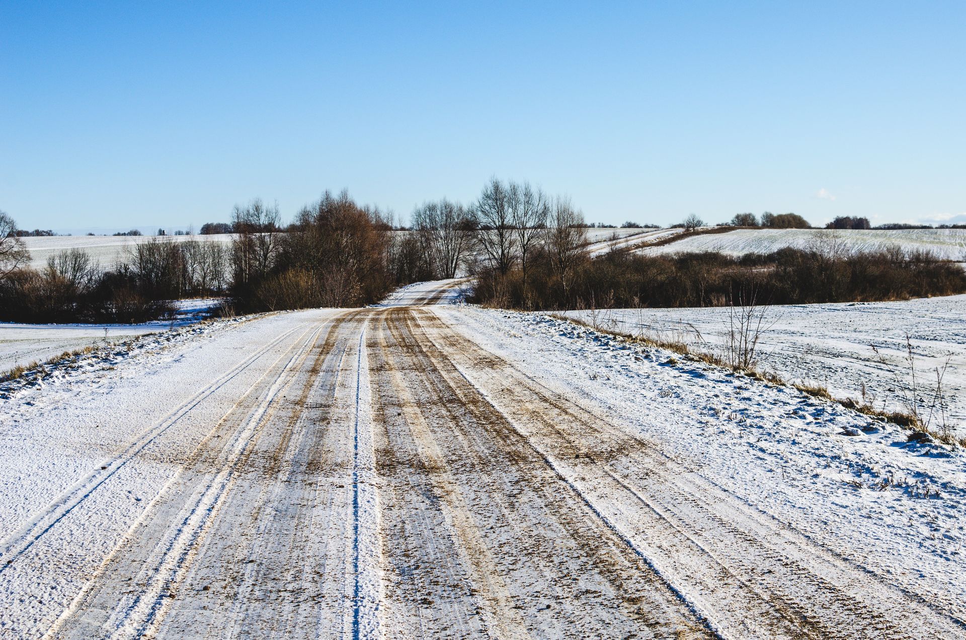 Un chemin de terre au milieu d'un champ enneigé.