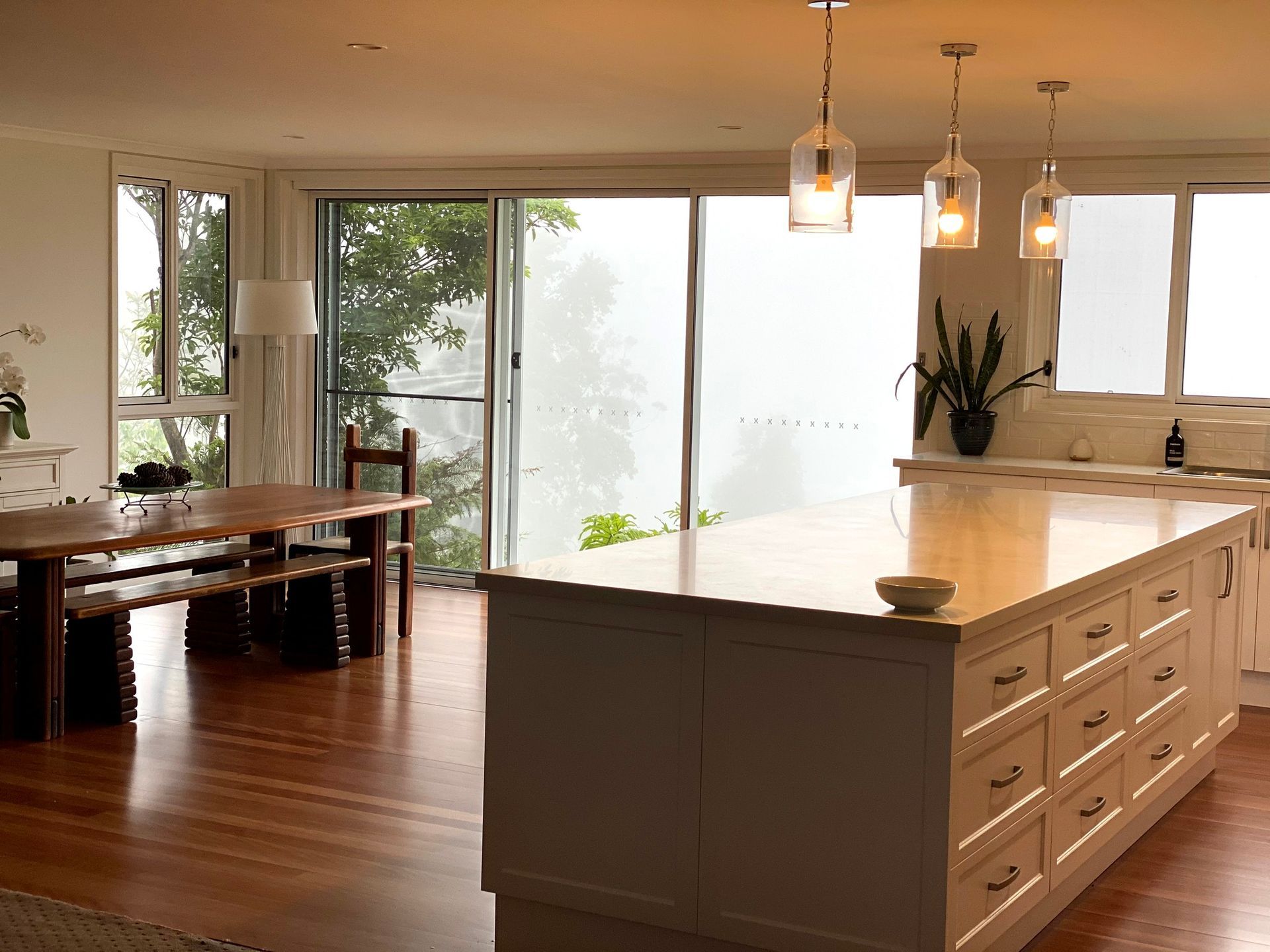 Kitchen With Island, Table, and Windows Overlooking a Misty Landscape — BK Building Services Pty Ltd In Forster, NSW
