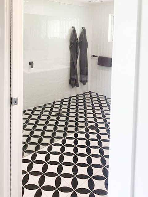 White tiled bathroom with black-and-white patterned floor, towels hanging on the wall, and a towel bar — BK Building Services Pty Ltd In Forster, NSW