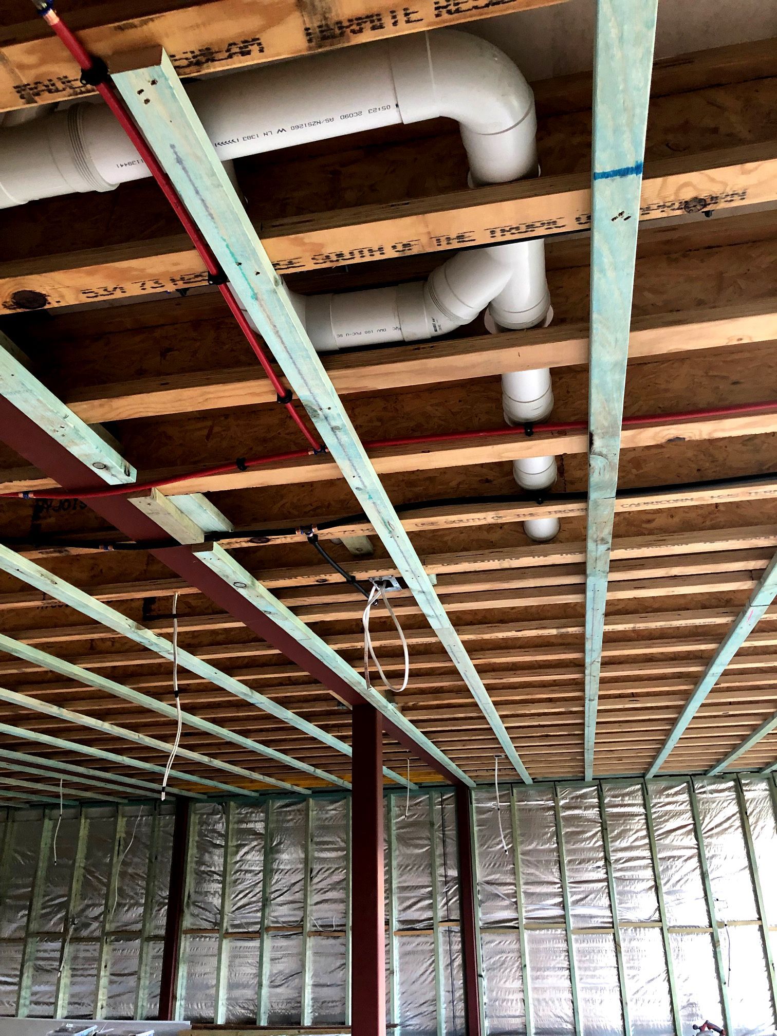 Exposed basement ceiling with white ducts, joists, and green metal framing before drywall installation — BK Building Services Pty Ltd In Forster, NSW