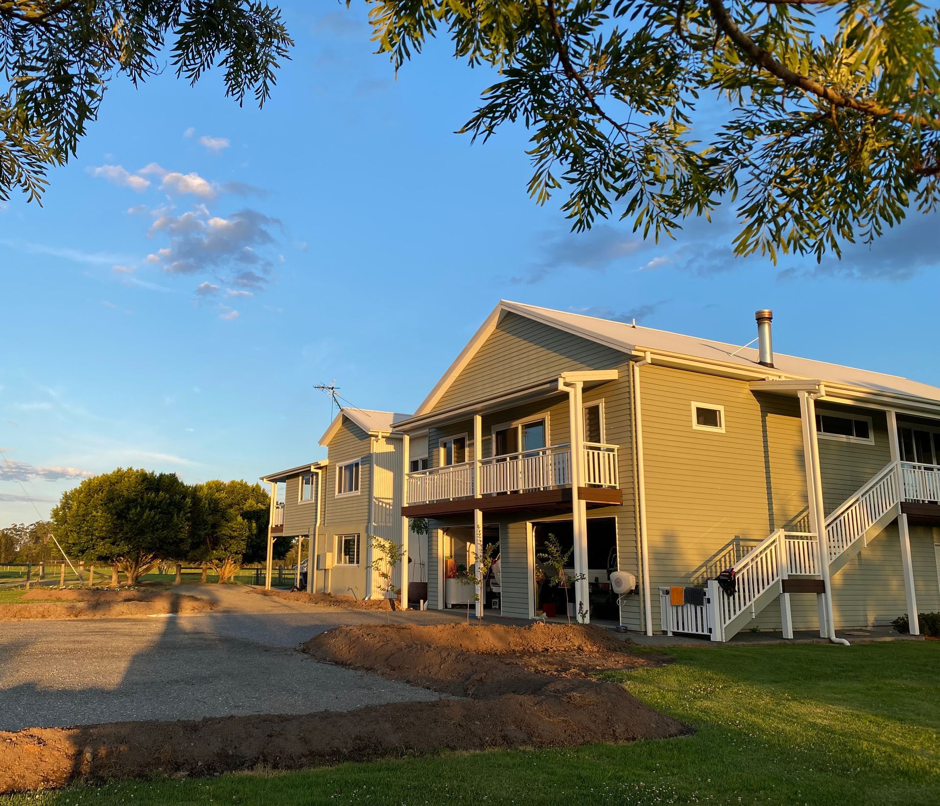 Two-story Building With Balconies, Steps, and Siding, Bathed in Golden Sunlight — BK Building Services Pty Ltd In Taree, NSW