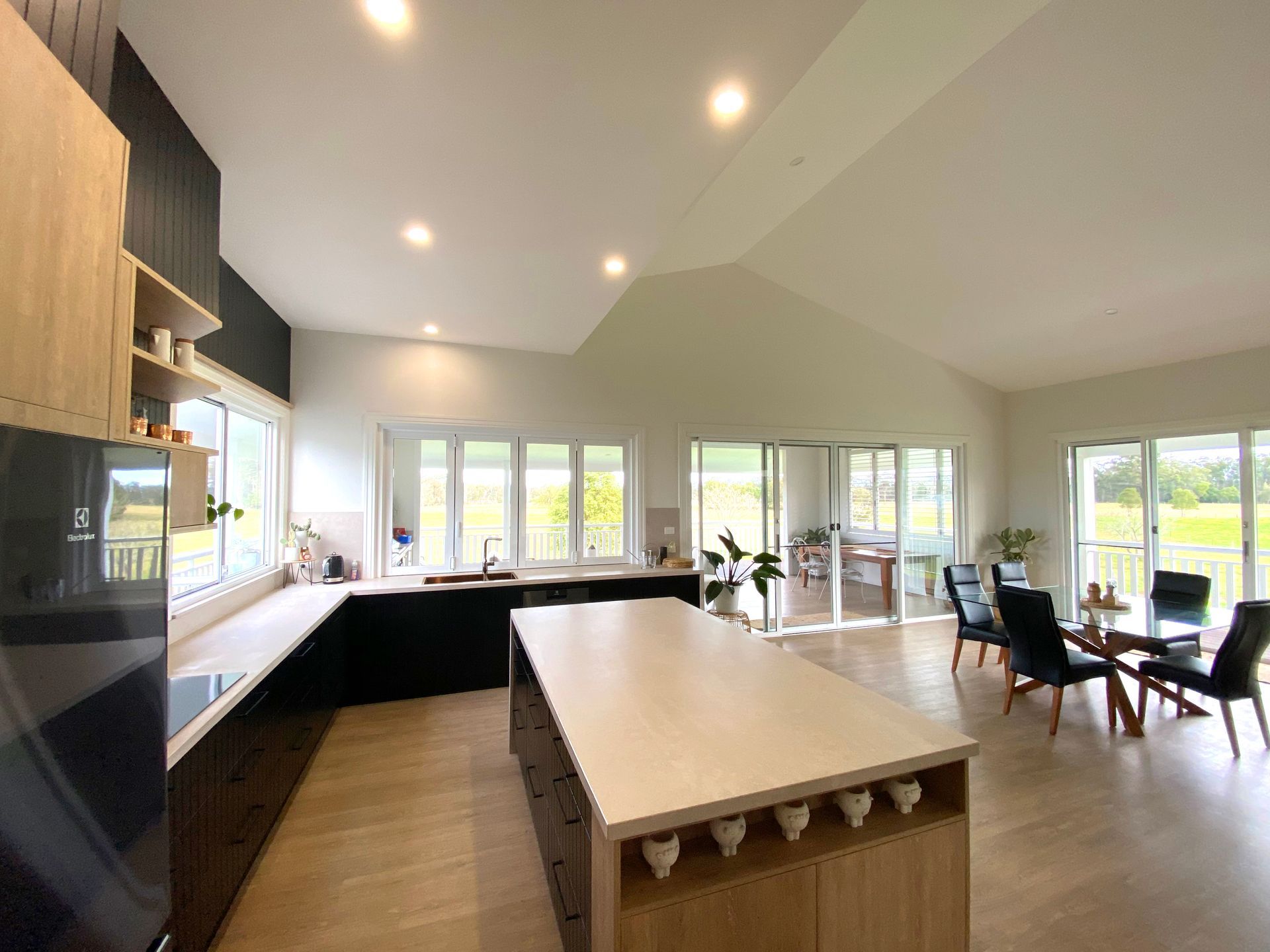 Open-plan Kitchen With Light Wood Floors, a Large Island, and Black Cabinet — BK Building Services Pty Ltd In Taree, NSW