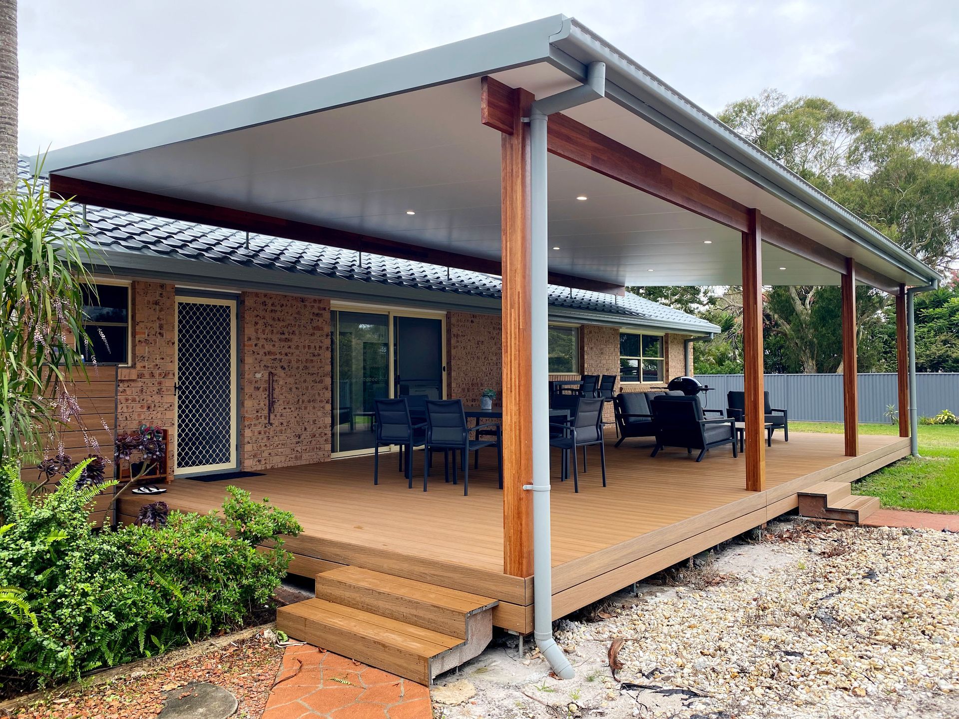 Deck With a Grey Roof and Wood Posts Extending From a Brick House — BK Building Services Pty Ltd In Taree, NSW