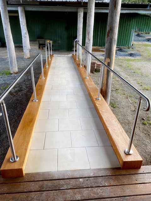 Accessible ramp with tiled floor, stainless handrails, and wooden side curbs leading to a building entrance — BK Building Services Pty Ltd In Forster, NSW
