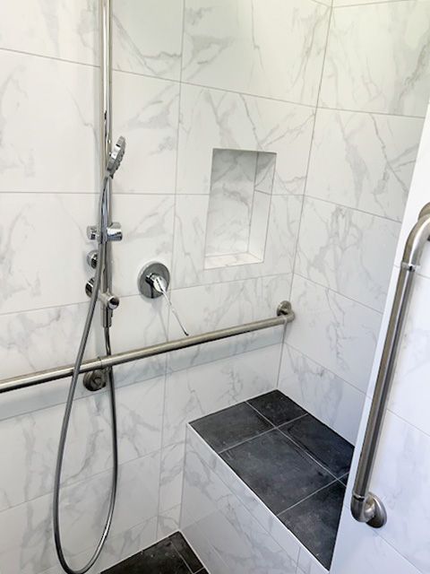 Walk-in shower with chrome grab bars, handheld showerhead, and black tile bench seat — BK Building Services Pty Ltd In Forster, NSW