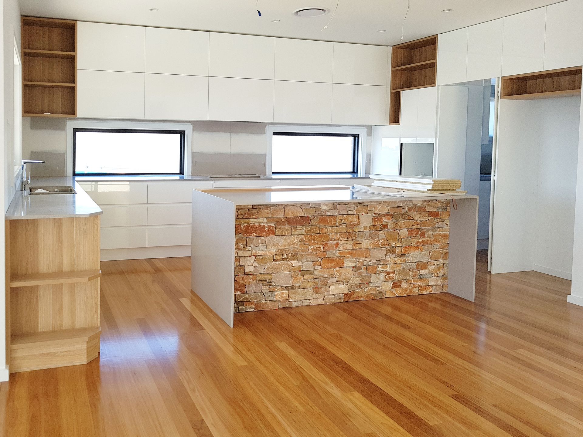 Modern Kitchen With Wooden Floors, White Cabinets, and a Stone-faced Island — BK Building Services Pty Ltd In Taree, NSW