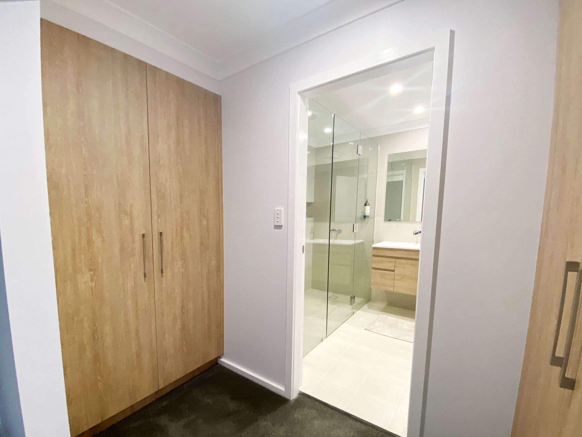 Bedroom Closet and Bathroom Entrance With Wood Cabinets and Glass Door — BK Building Services Pty Ltd In Taree, NSW