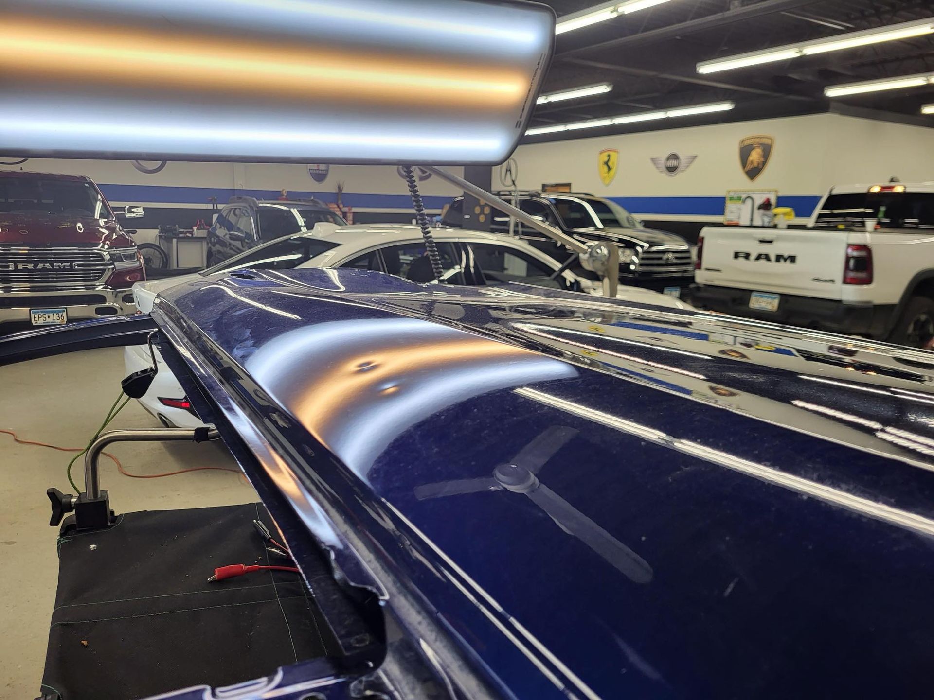 A ram truck is parked in a garage next to a blue car