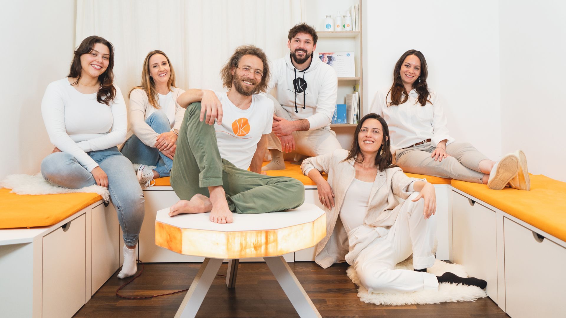 Eine Gruppe von sieben lächelnden Personen in einem hellen Raum. 