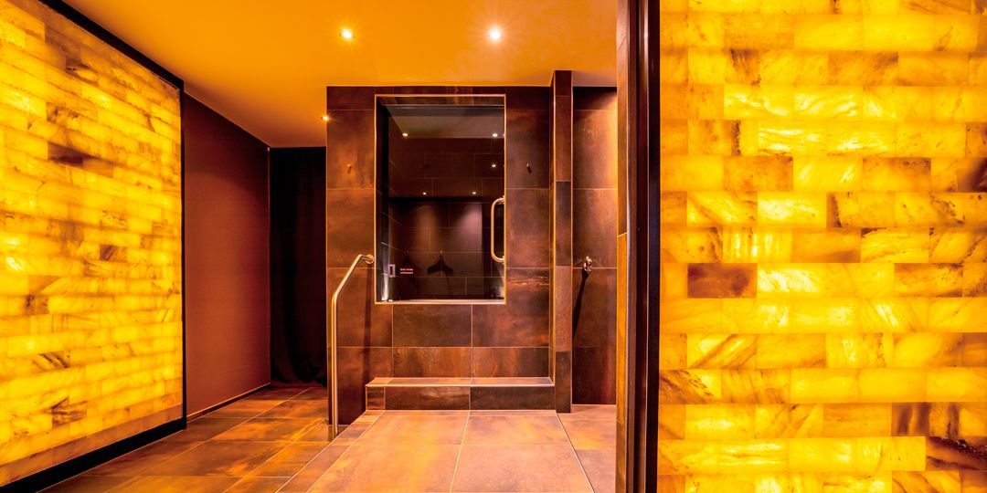 Ein warm beleuchteter Spa-Eingang mit beleuchteten Wänden und einer Glastür.