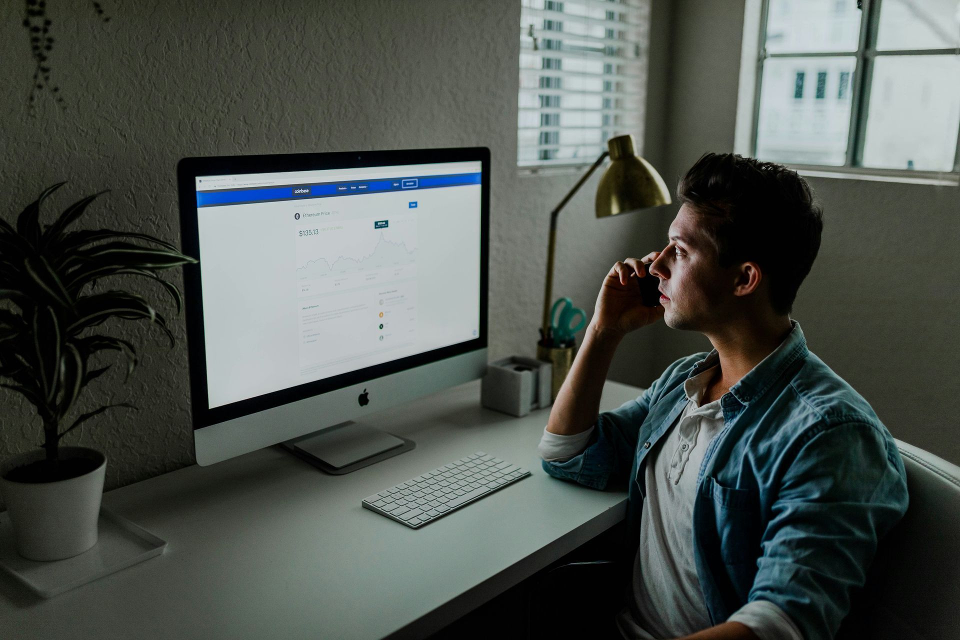 A man is sitting at a desk looking at a computer screen.