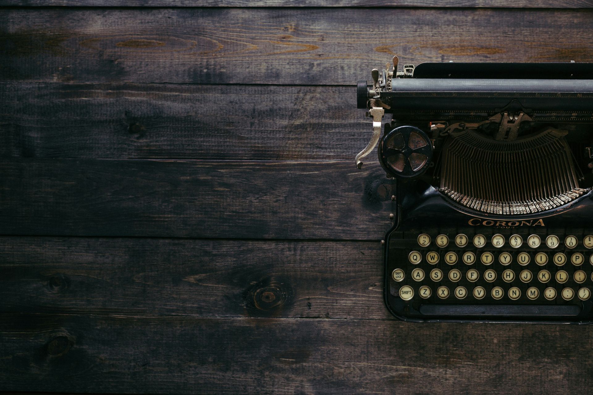 An old typewriter is sitting on a wooden table.