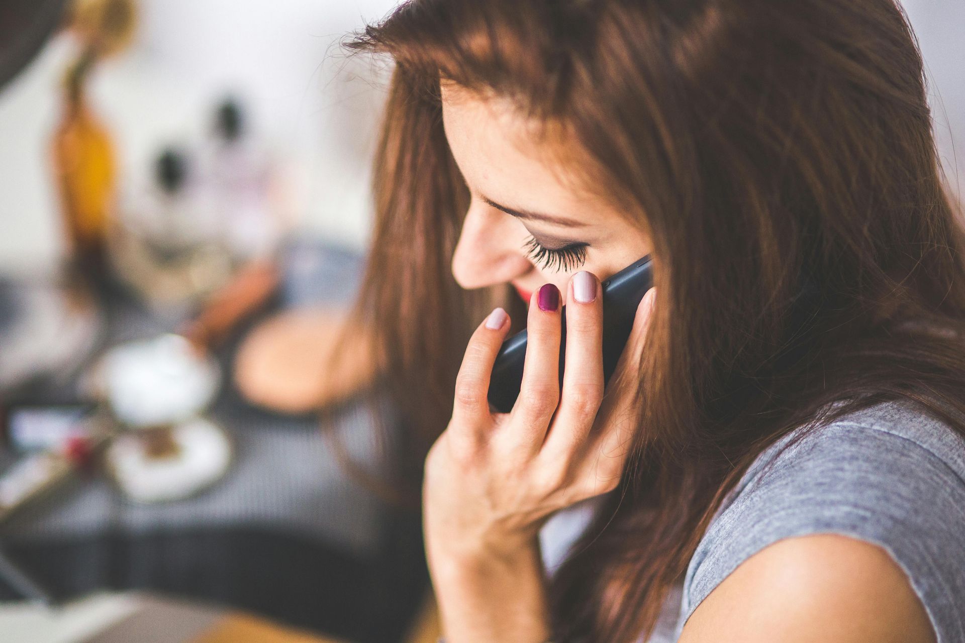 A woman is talking on a cell phone while sitting at a table.