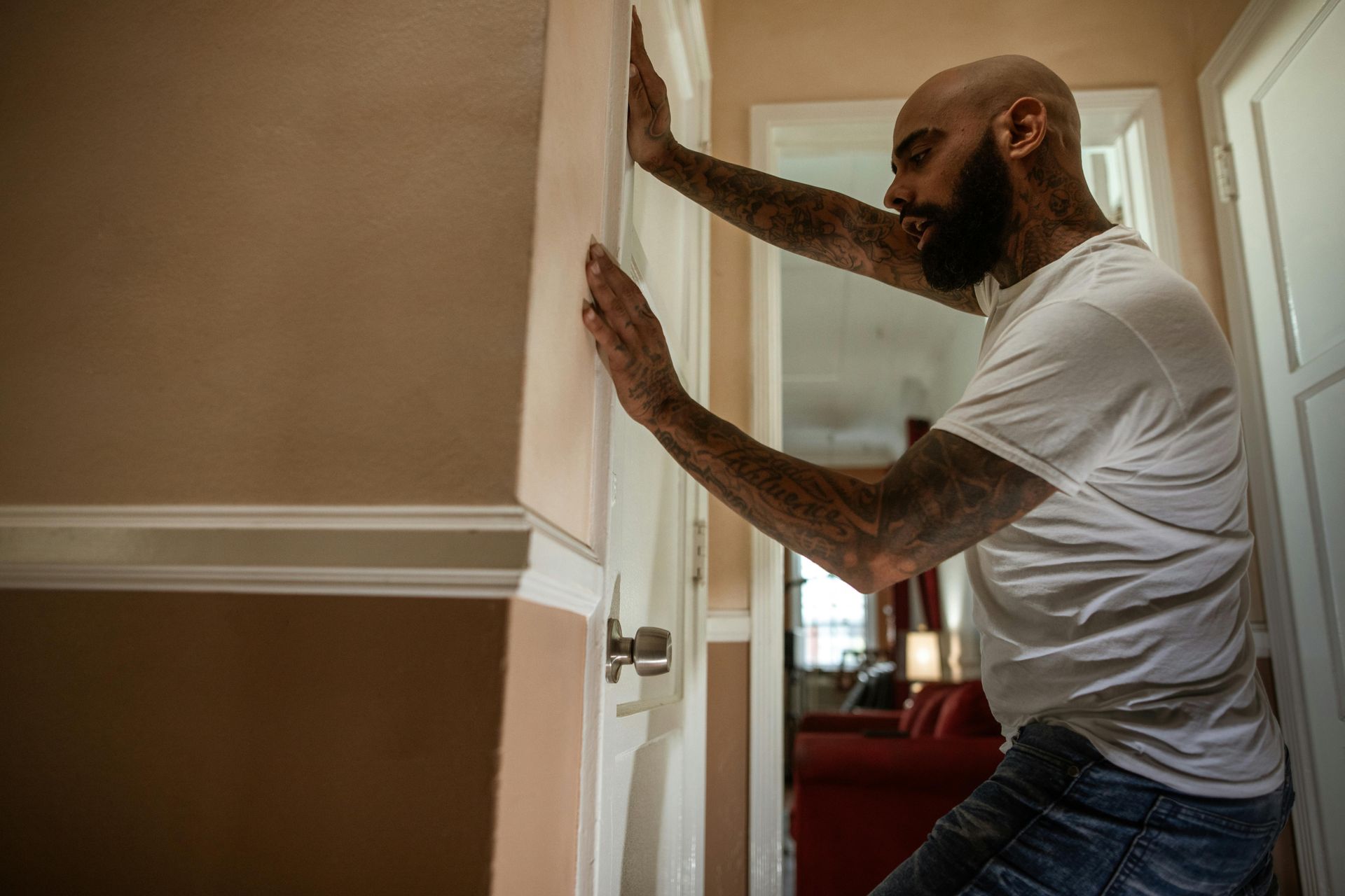 A man is leaning against a door in a hallway.