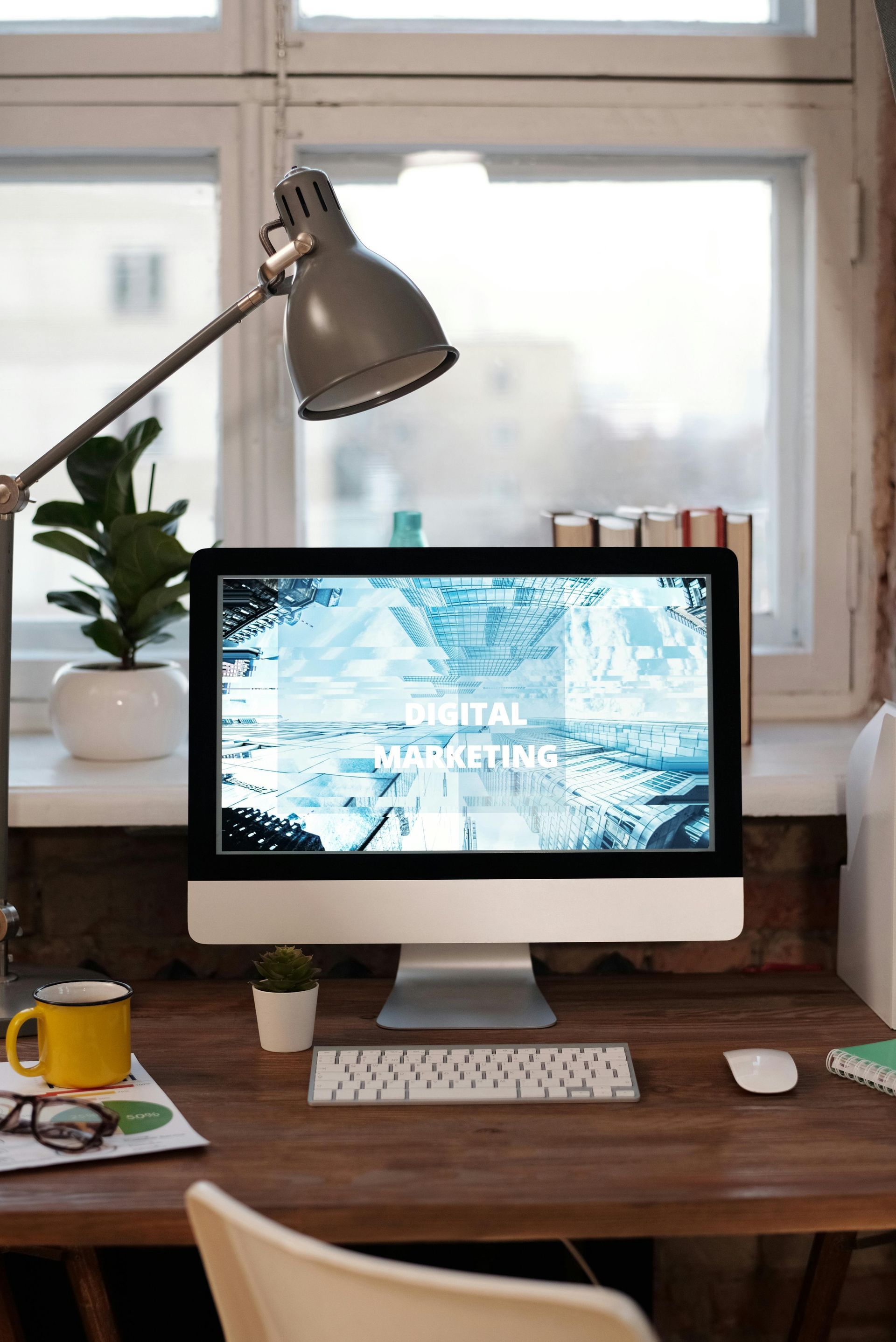 A computer is sitting on a wooden desk next to a lamp.