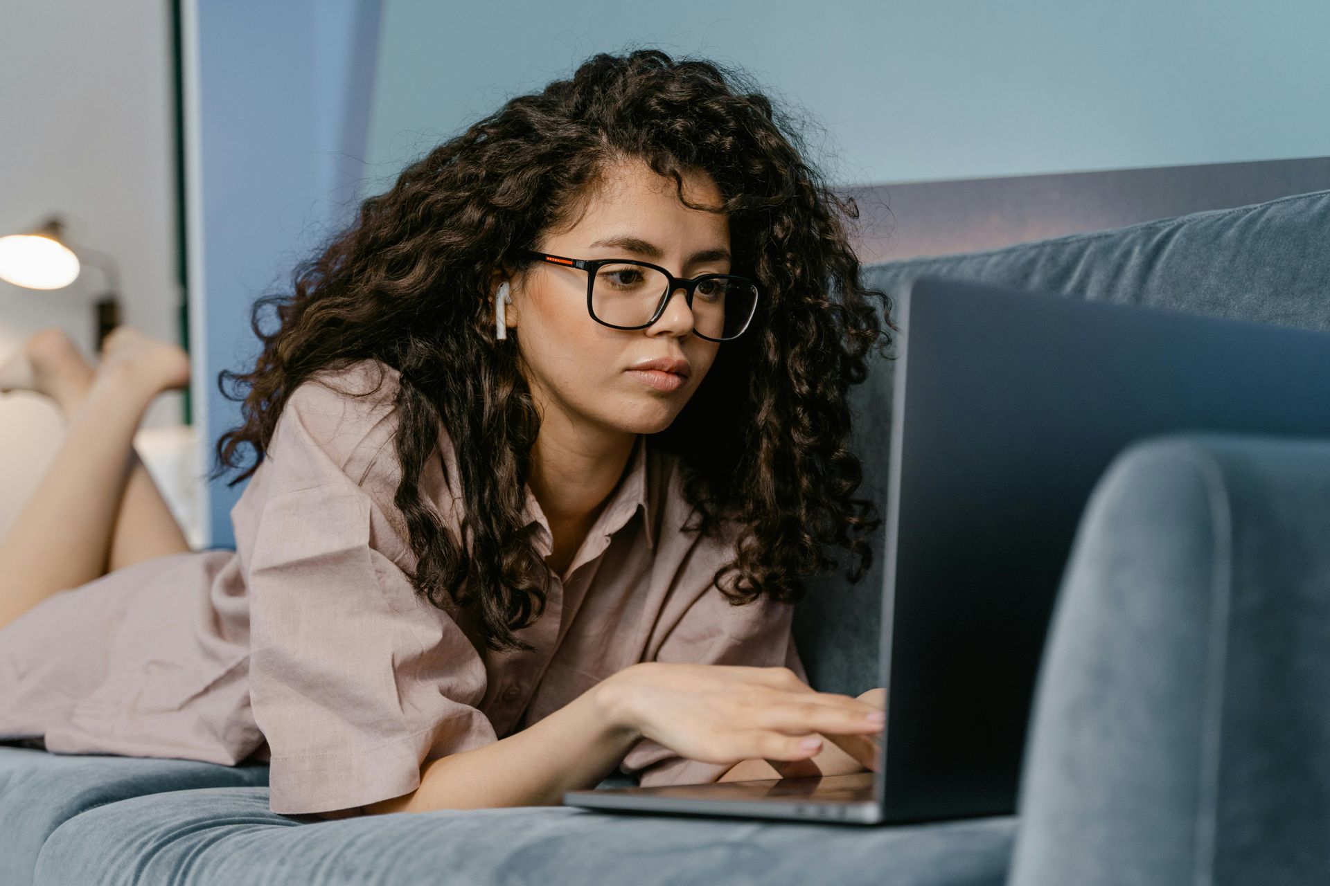 A woman is laying on a couch using a laptop computer.