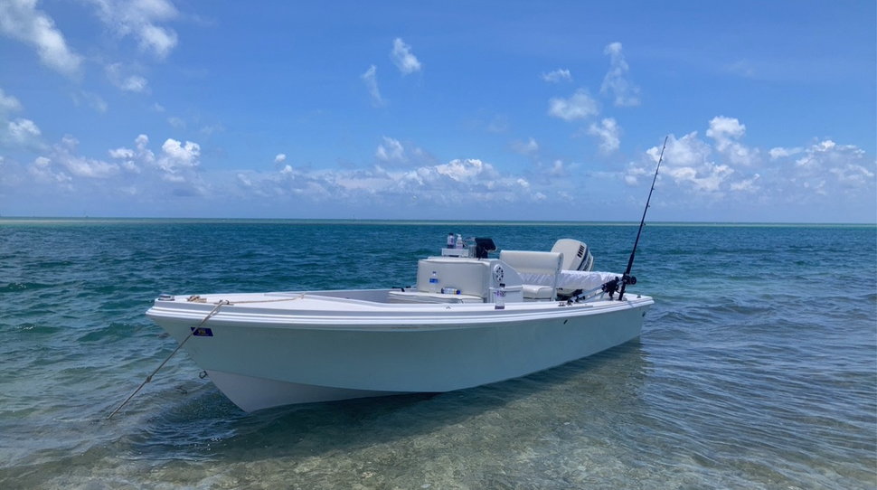 A shallow, clear lake with a white boat sitting near the shore.