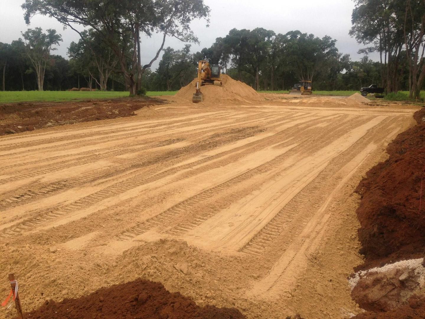 Construction site with graded sand, a bulldozer, and a small pile of sand.