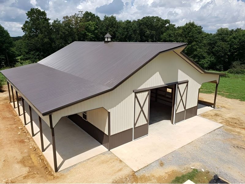 Brown and beige barn with a metal roof and open doors.