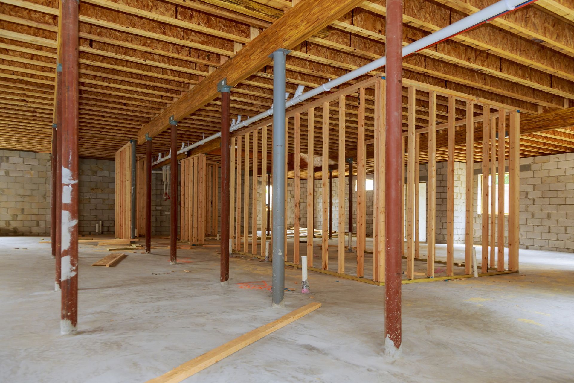 Basement interior under construction with wood framing and support beams.