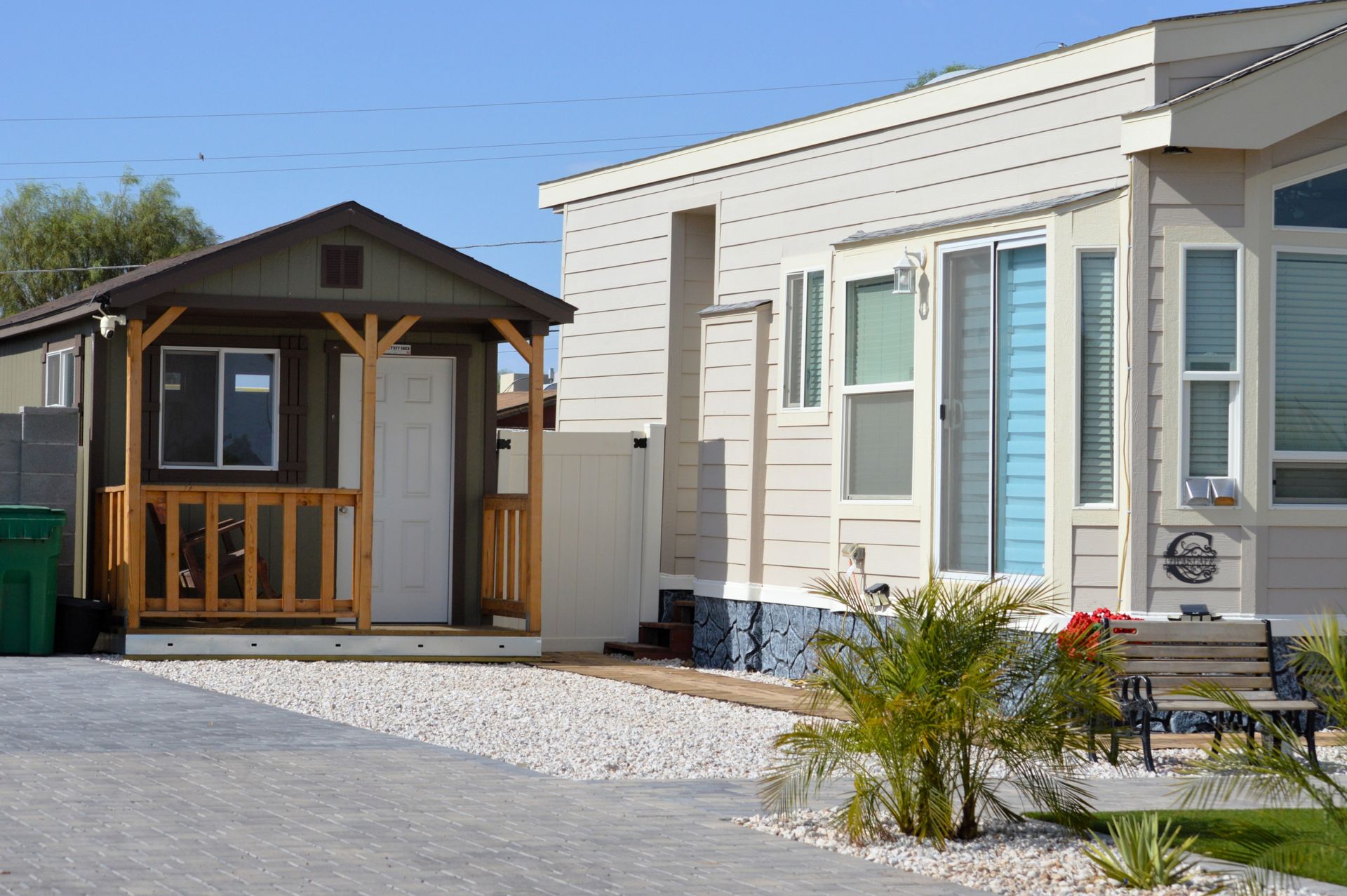 Small house next to a larger mobile home. The small house has a porch, and the mobile home has large windows.