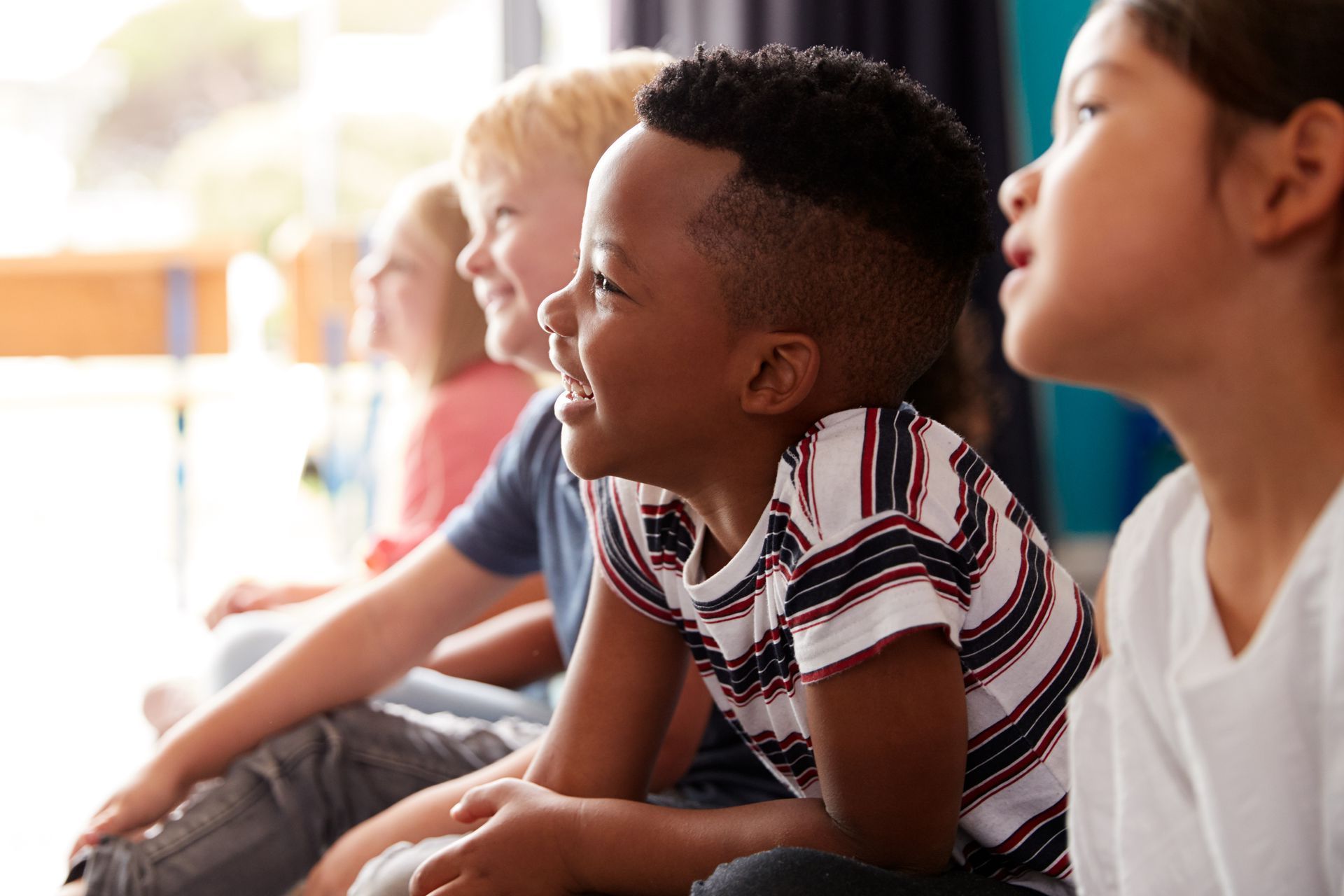 A group of children are sitting on the floor watching a movie.
