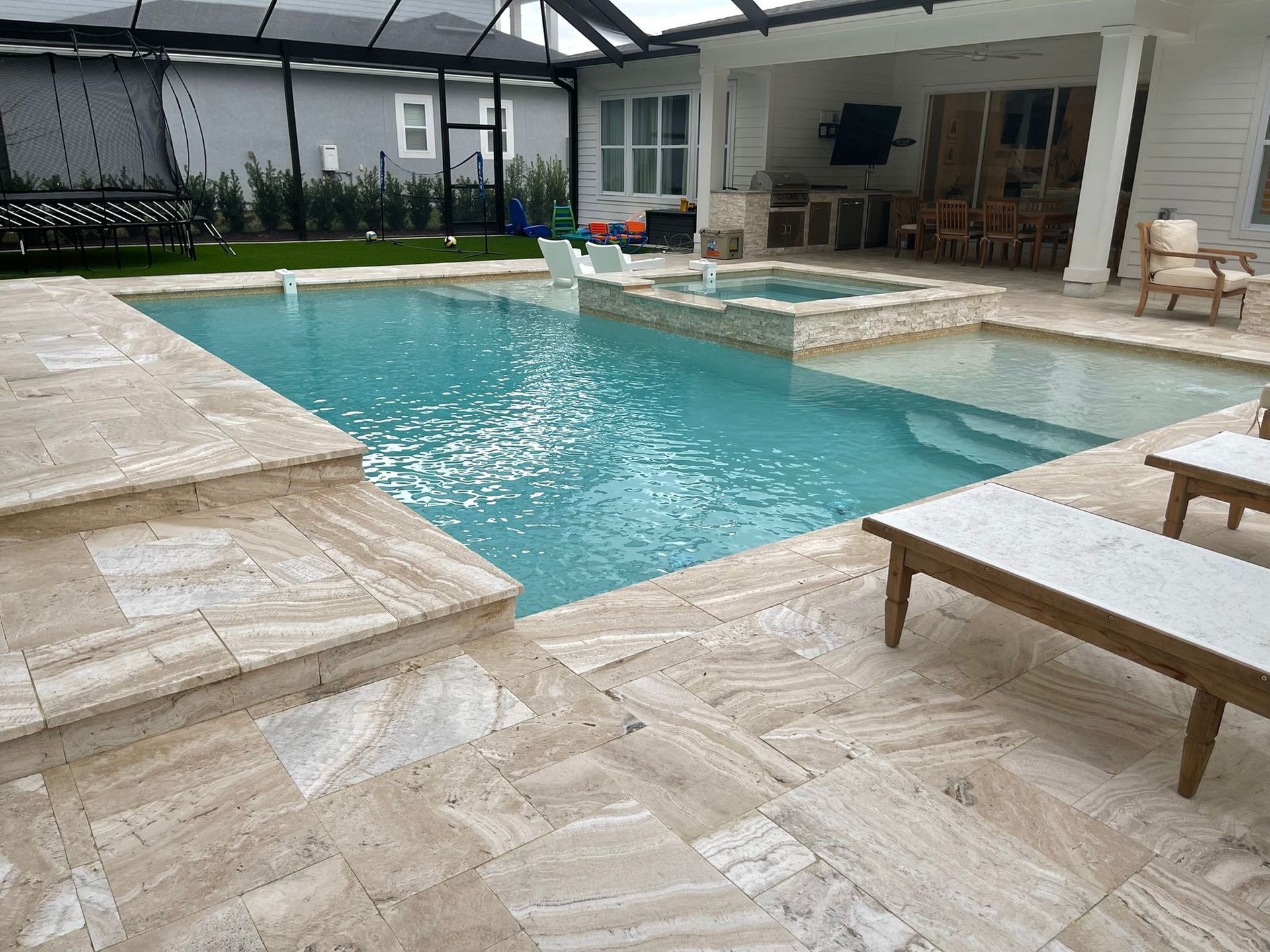 Swimming pool with paver steps and patio, adjacent to a spa and covered outdoor area.