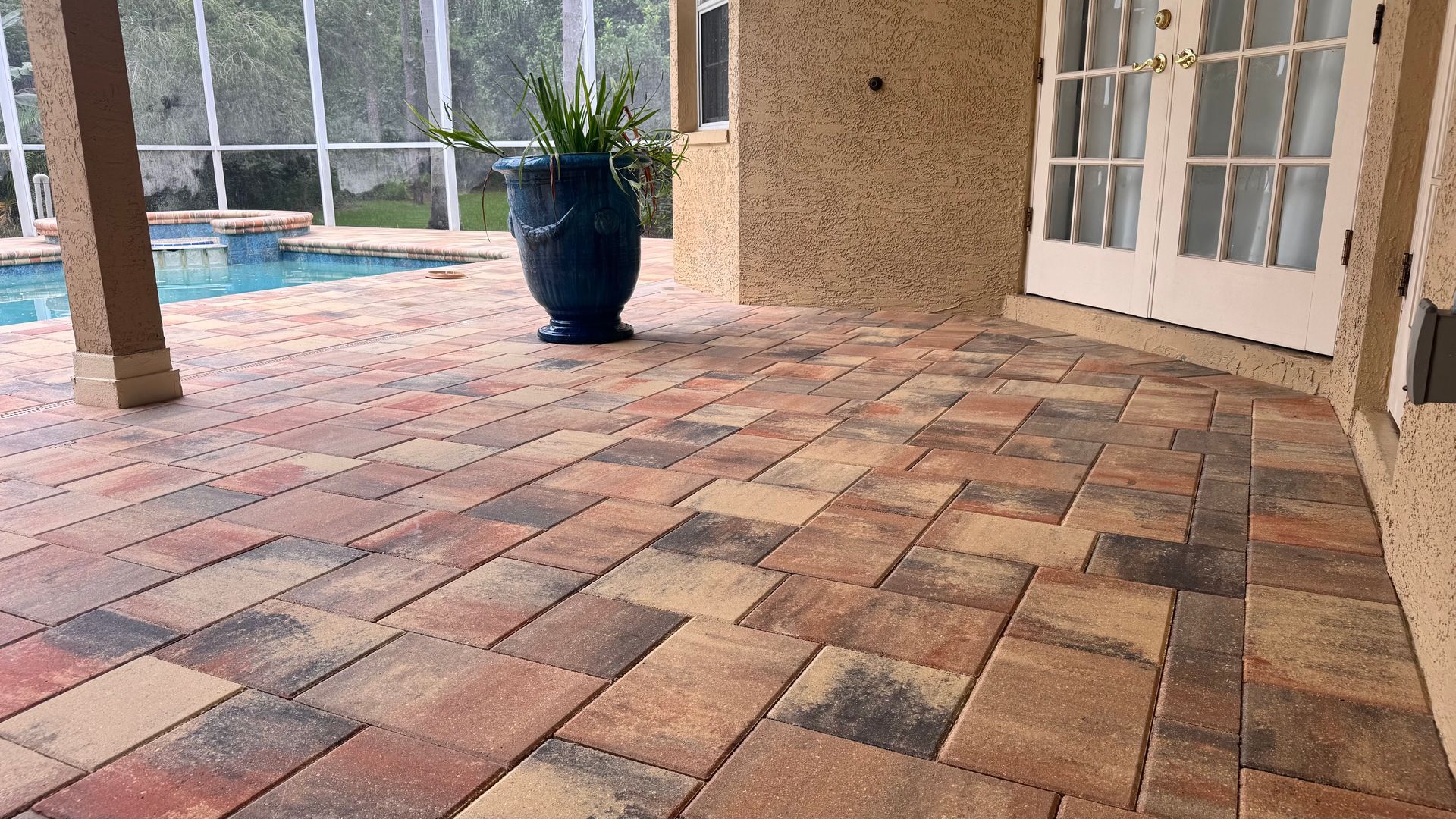 Brick patio with a pool and a potted plant next to a house with French doors.