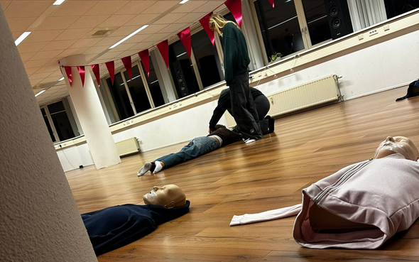 Reanimatietraining: Iemand voert borstcompressies uit op een oefenpop. 