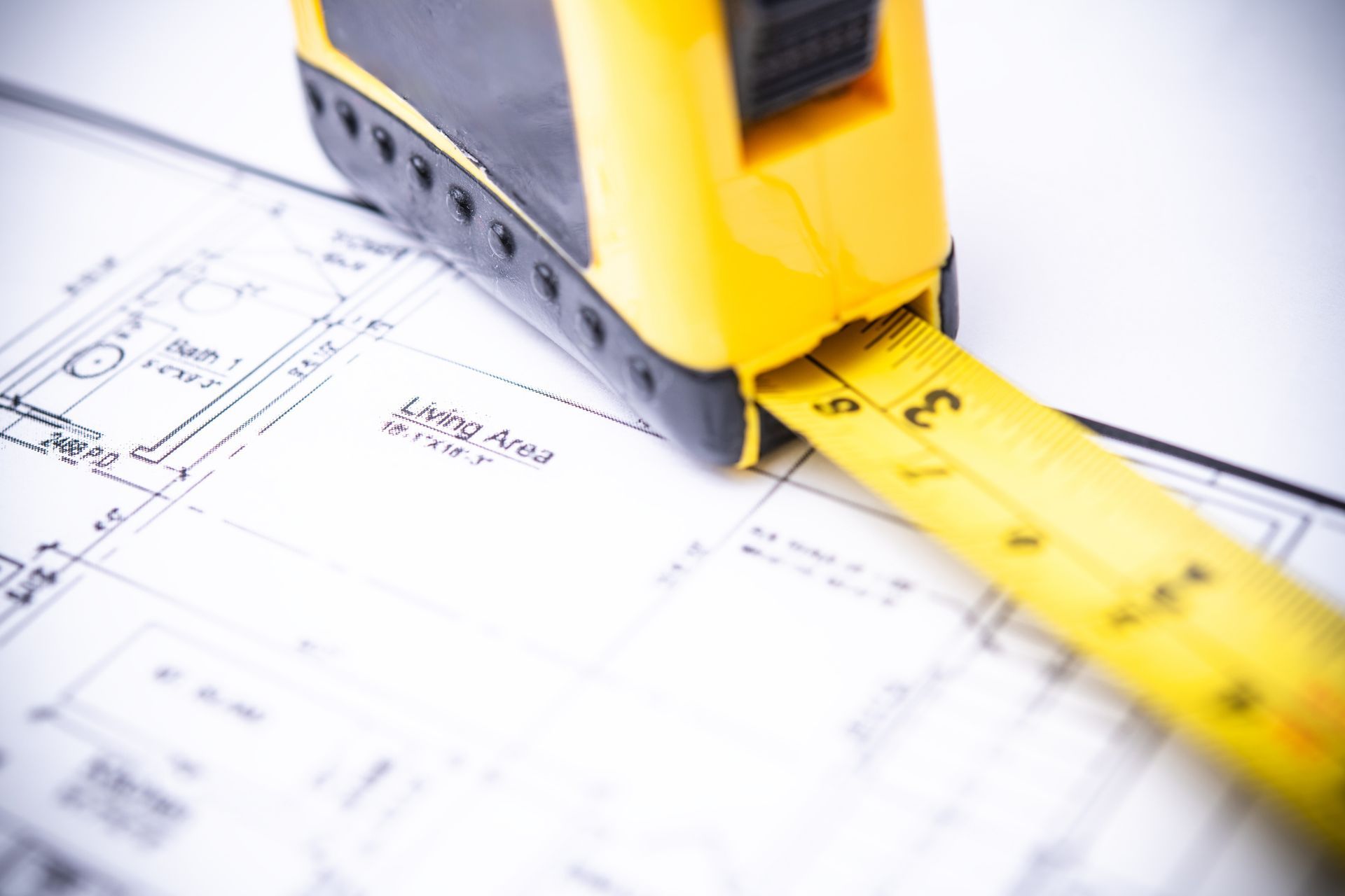 Yellow tape measure on top of a blueprint, measuring the 
