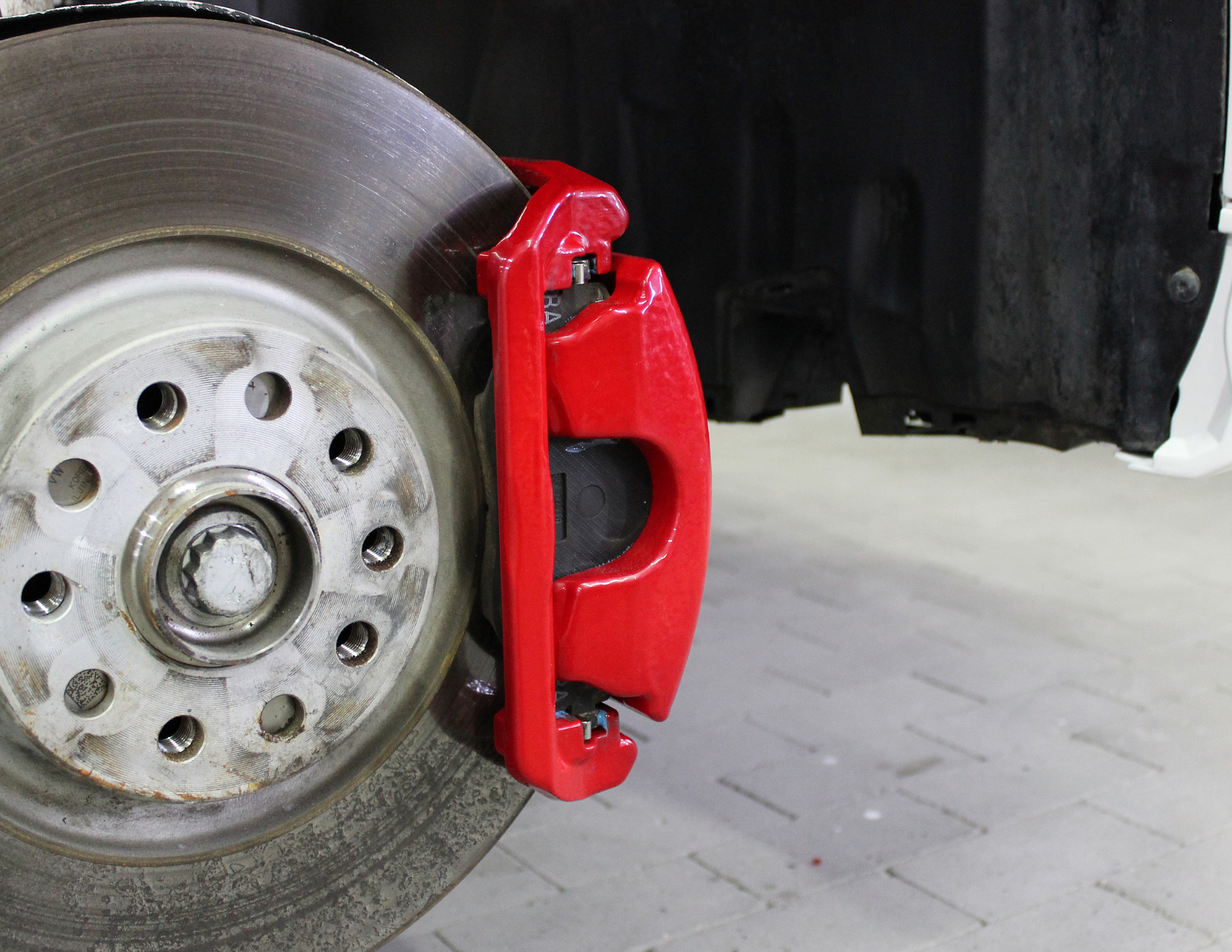 Red painted car brake caliper and rotor.