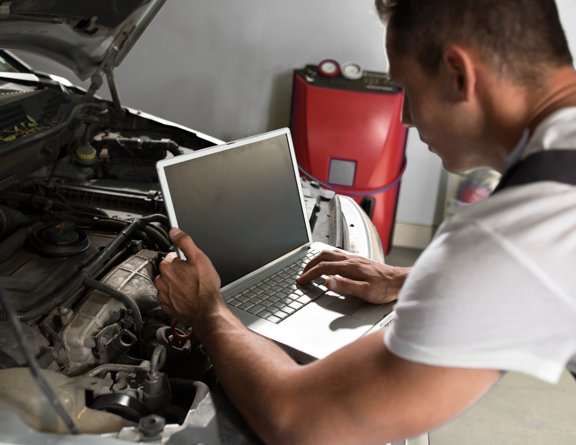 Mechanic using a laptop to diagnose a car engine.