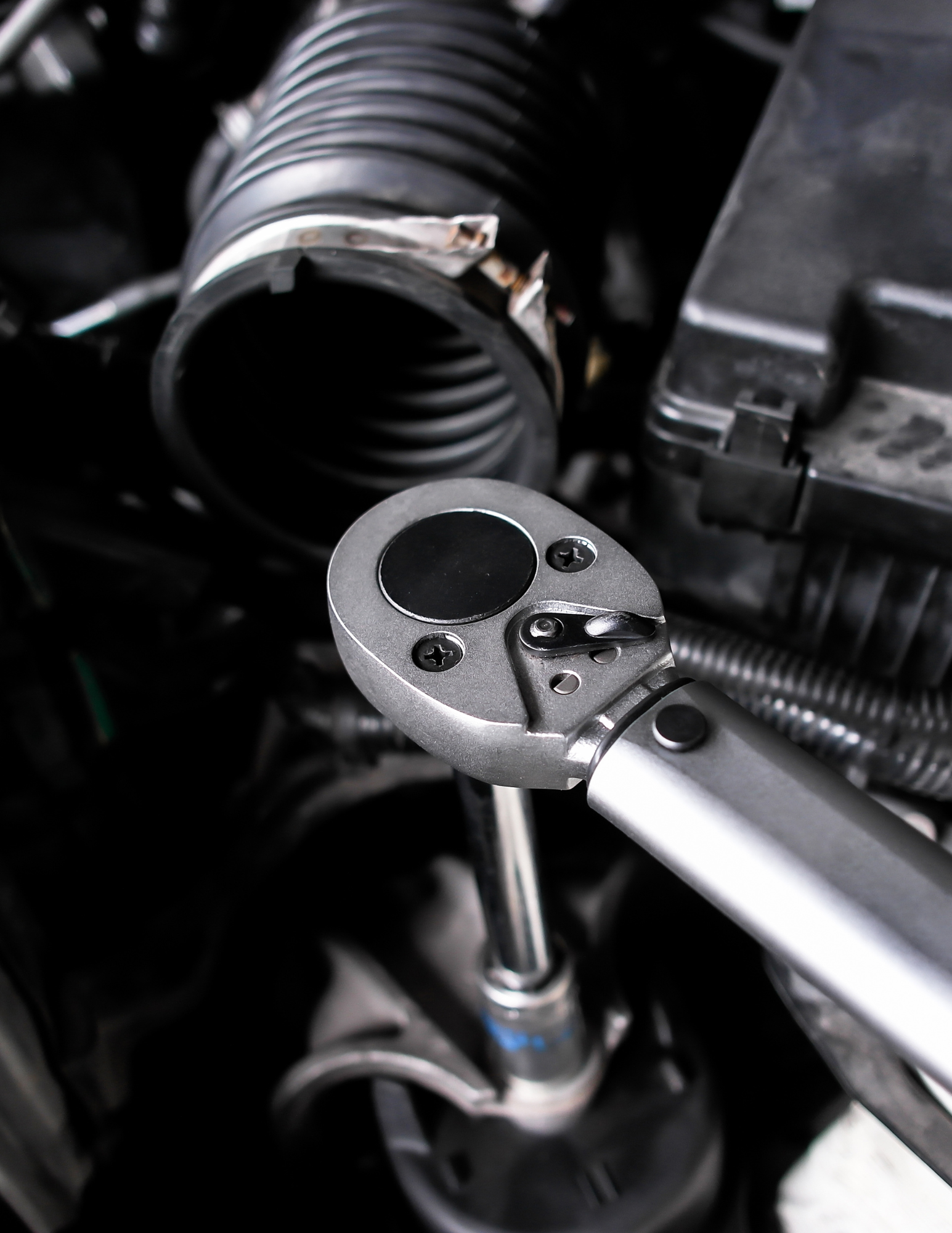 Wrench tightening a bolt in a car engine compartment.
