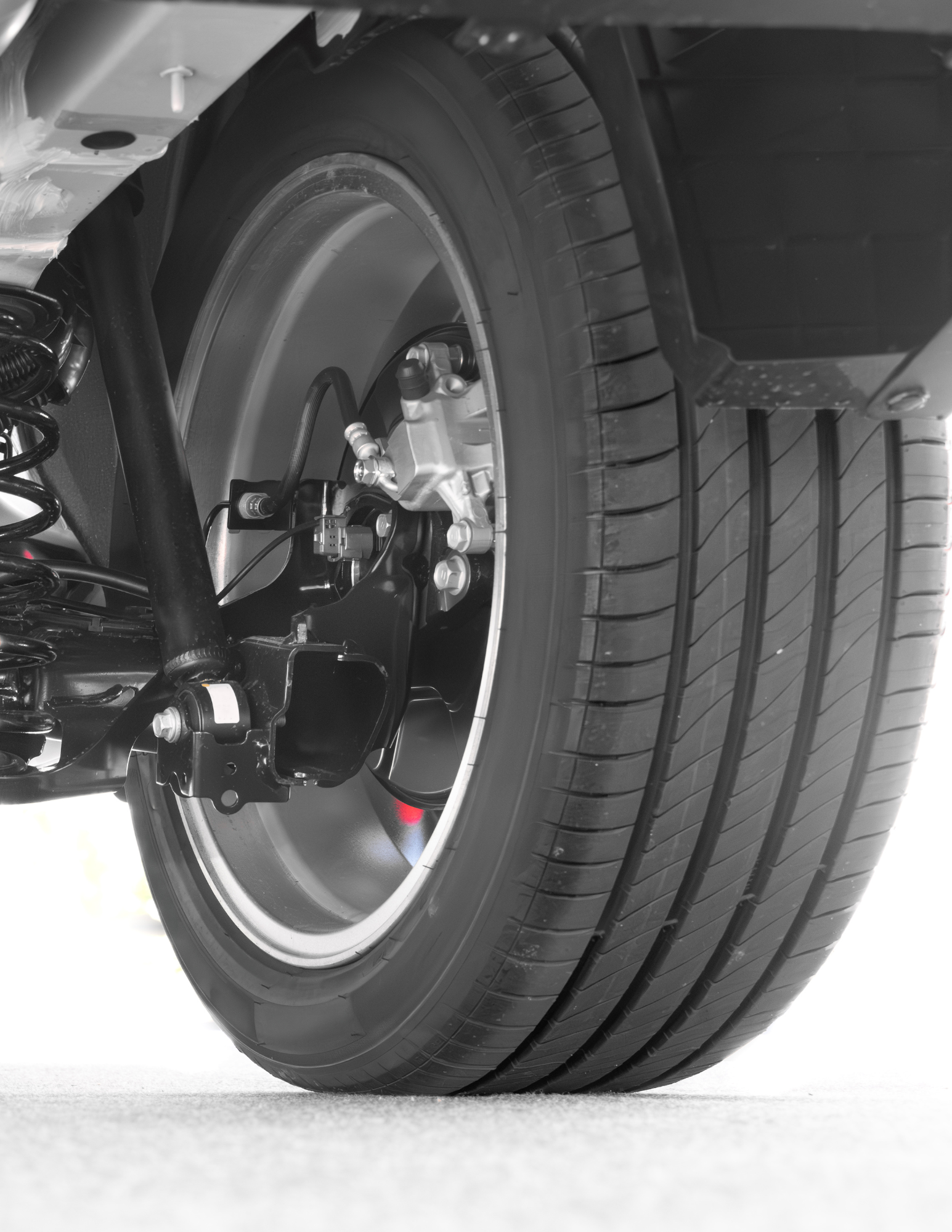 Close-up of a car's rear wheel and tire, showing the tire tread, brake components, and suspension.