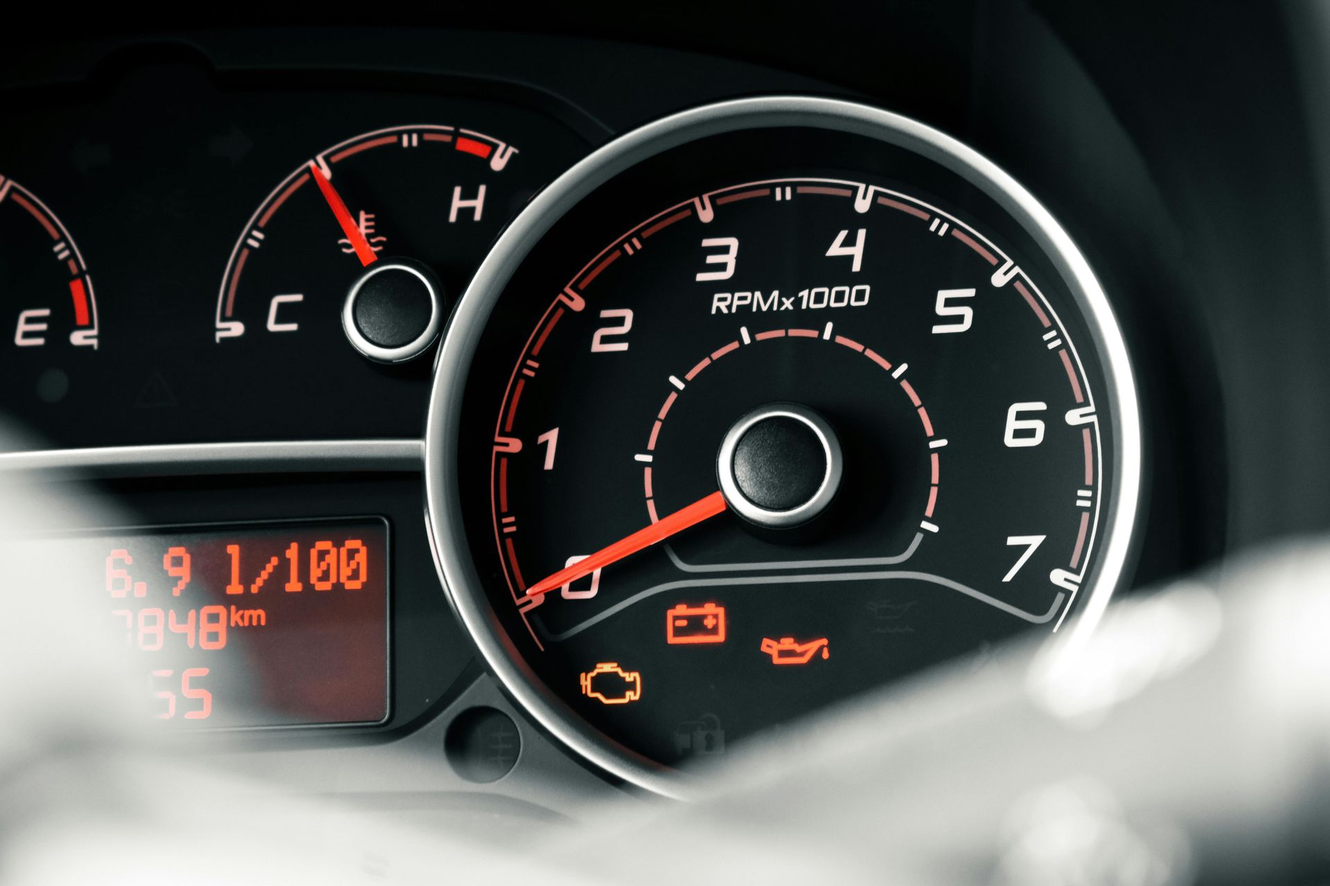 Car dashboard with speedometer and warning lights illuminated.