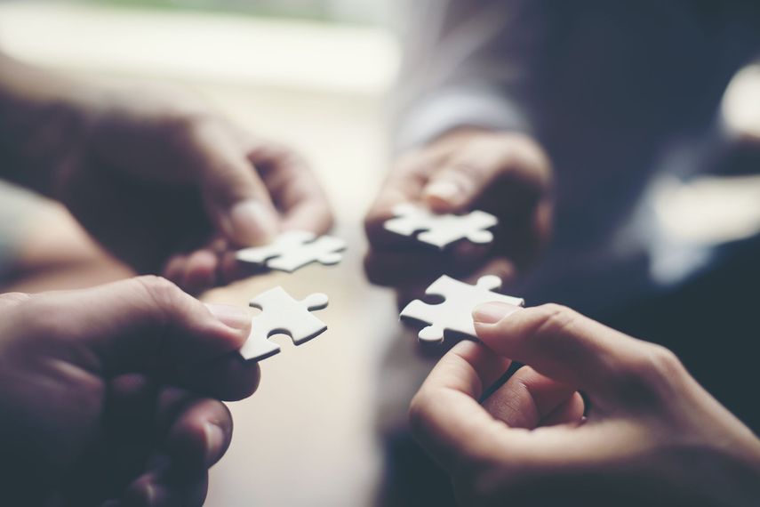 A group of people are holding puzzle pieces in their hands.