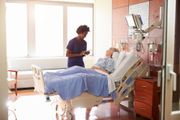 A nurse is standing next to a patient in a hospital bed.