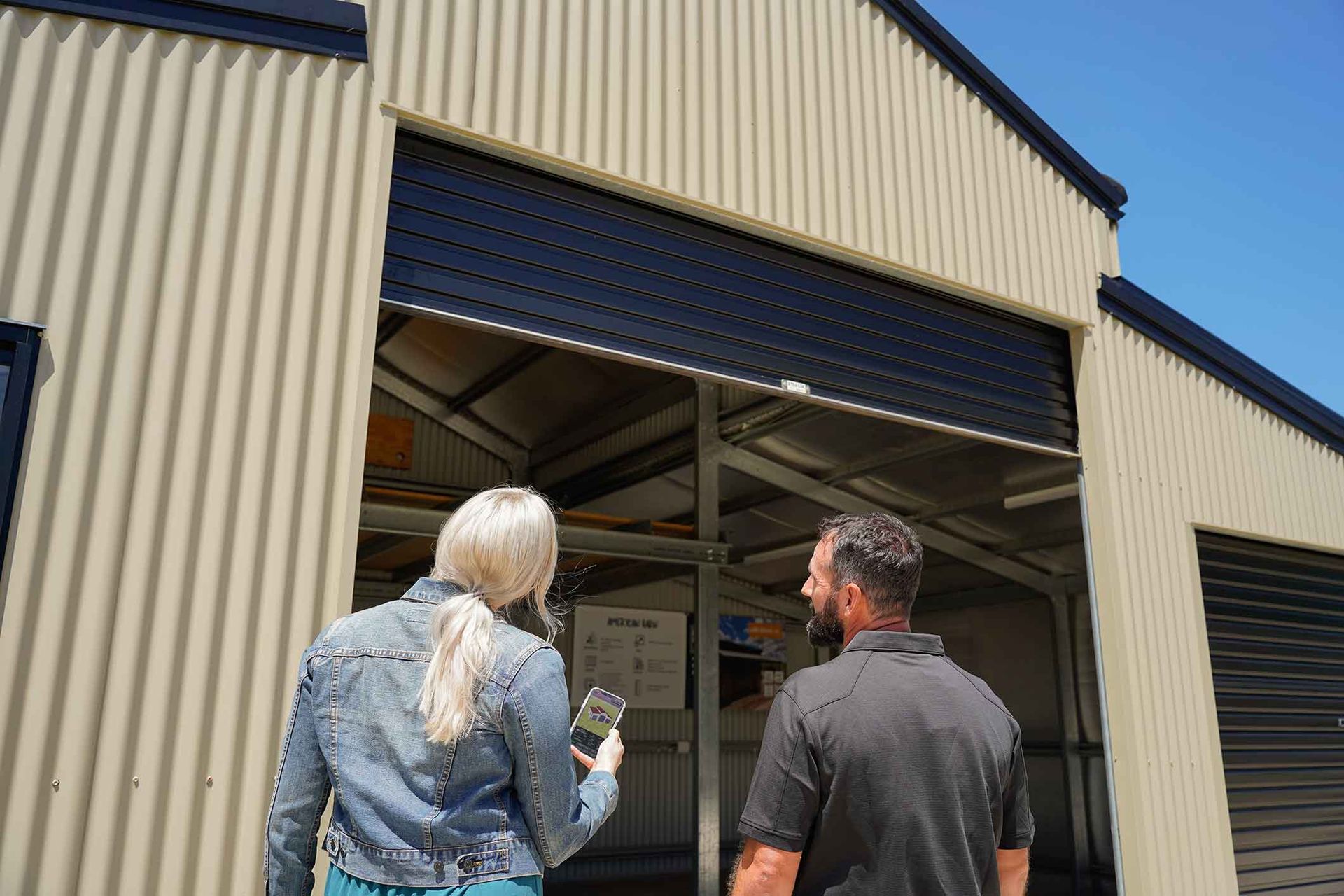 A Man And A Woman Are Standing In Front Of A Garage Door – South Kempsey NSW - Fair Dinkum Builds Macleay Valley Sheds
